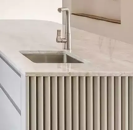 White fluted island panel below a stone benchtop and sink