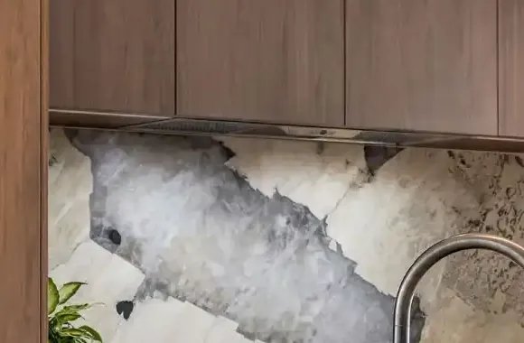 Stone splashback with bold grey and white veining under dark timber cabinets