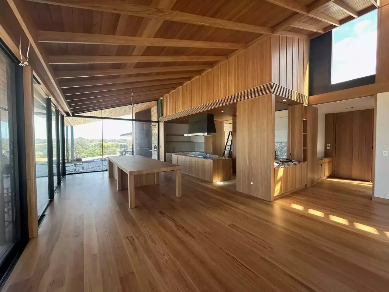 Open-plan room lined with timber joinery under a timber-battened ceiling