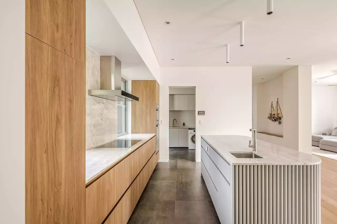 Kitchen with full-height timber cabinetry and a white fluted island