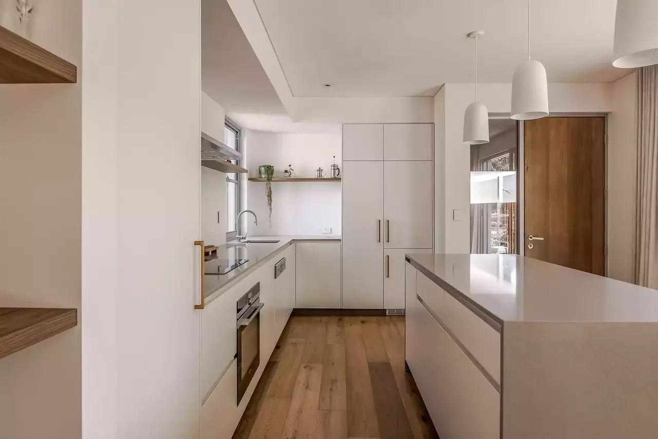 Kitchen studio with white cabinetry and a timber-lined wall