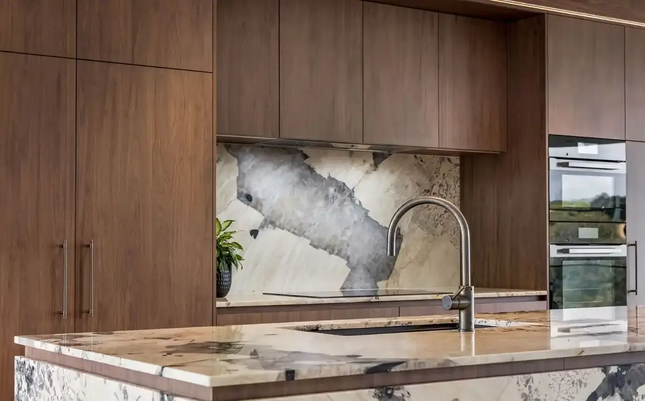 Dark timber kitchen with a dramatic stone splashback and matching stone benchtop