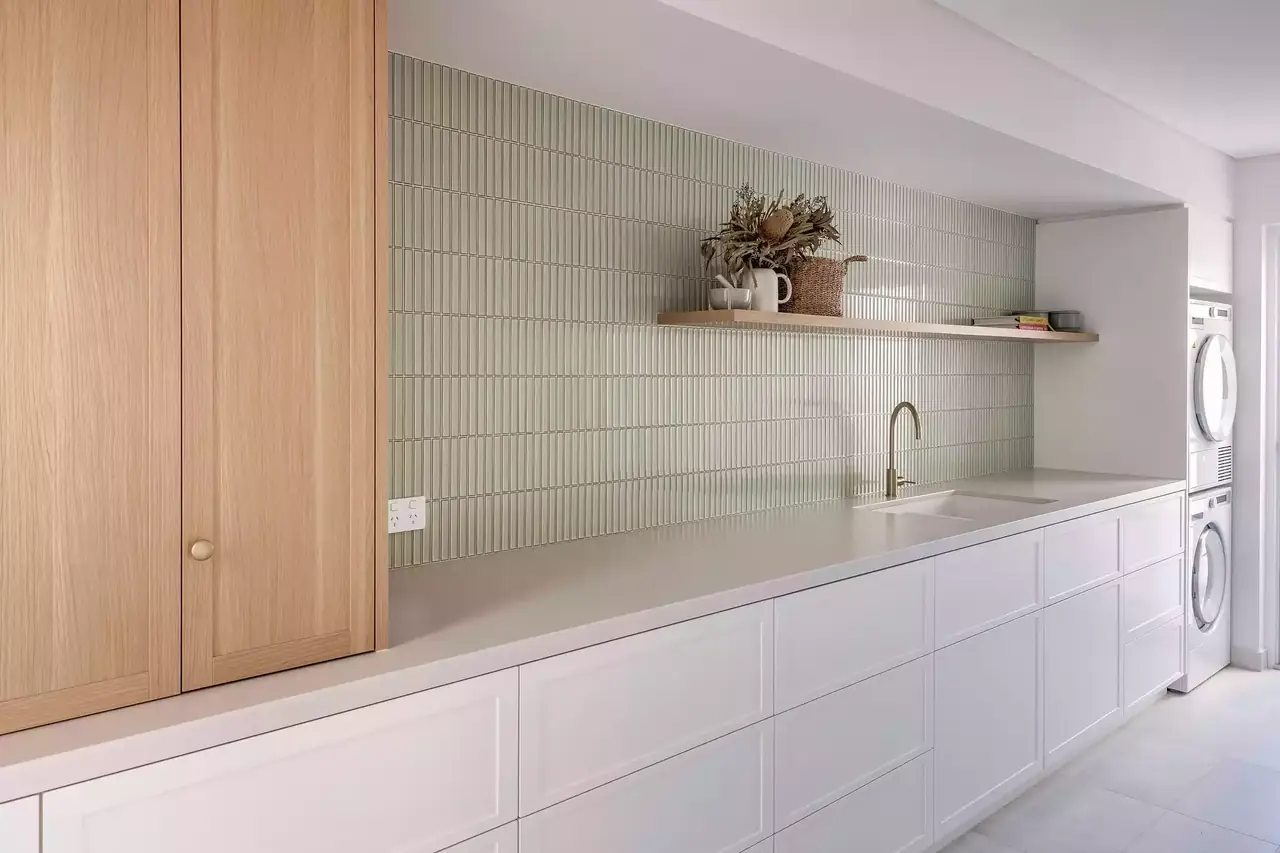 Laundry with timber tall cabinets, white drawers and stacked appliances
